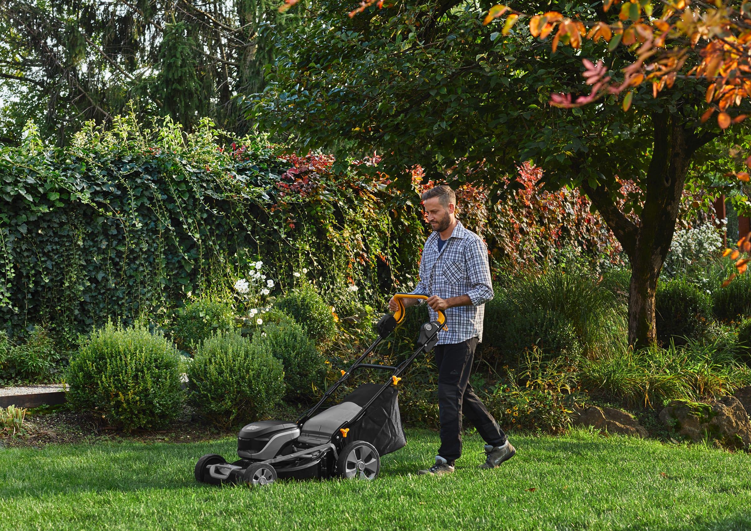 Mann mäht Rasen mit Rasenmäher