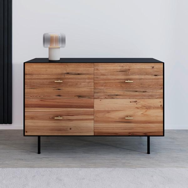 Moderná komoda s kombináciou prírodného dreva a čiernych detailov. Štyri zásuvky s elegantnými zlatými úchytkami poskytujú praktický úložný priestor. Ideálna voľba pre štýlový a funkčný interiér.
