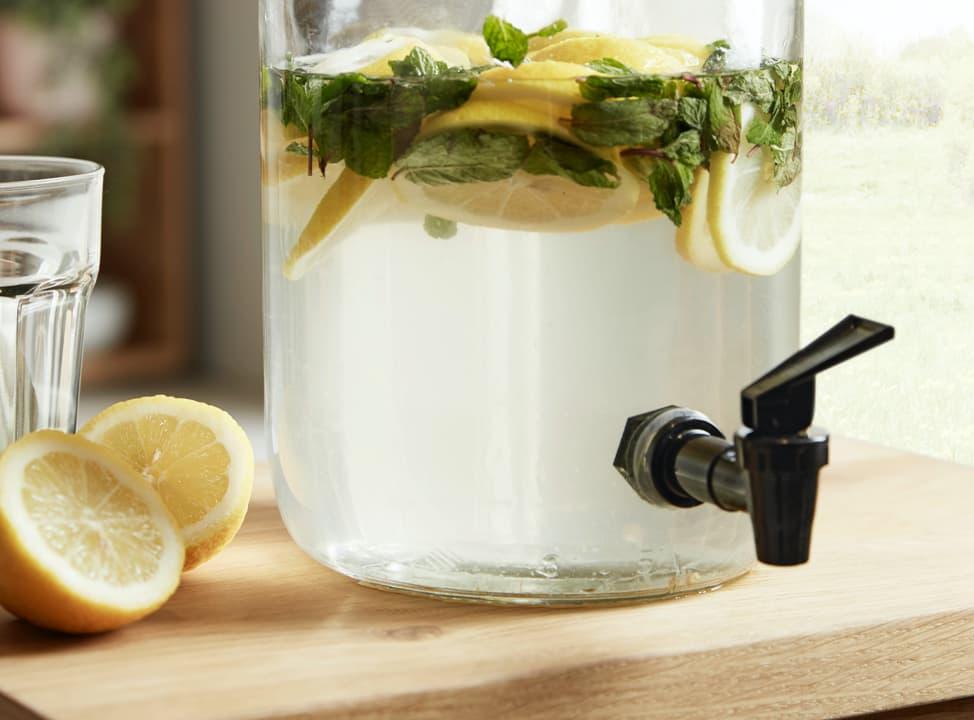 Saft mit Zitronenscheiben in Glasbehälter