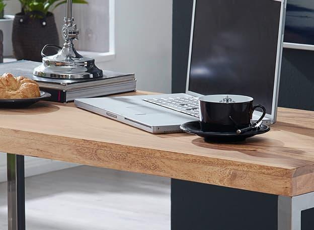 Kaffeetasse neben Laptop auf Holztisch