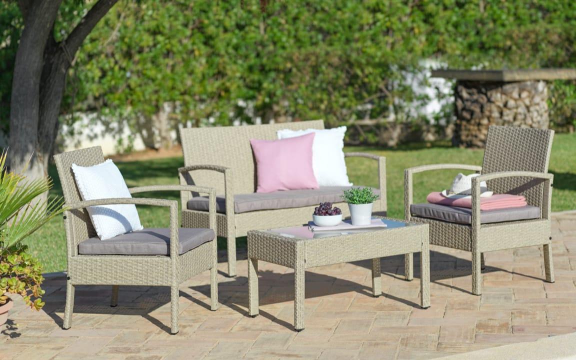 Sitzgruppe in Rattan-Optik auf Steinboden im Garten
