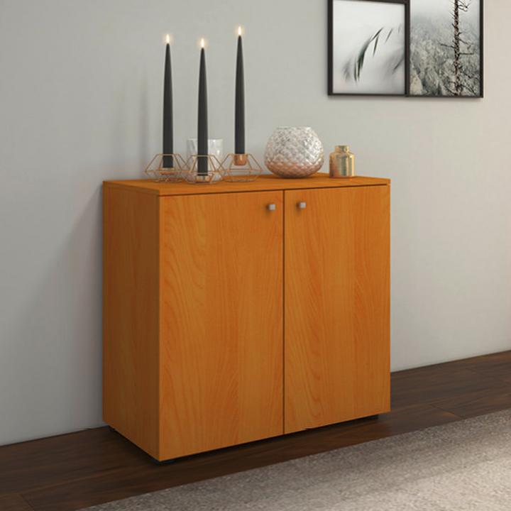 Moderná komoda v teplom drevenom dekore s dvojitými dvierkami. Jednoduchý a elegantný dizajn, ideálny na uskladnenie vecí v obývačke, predsieni alebo spálni. Skvelo dopĺňa interiér s minimalistickými dekoráciami.