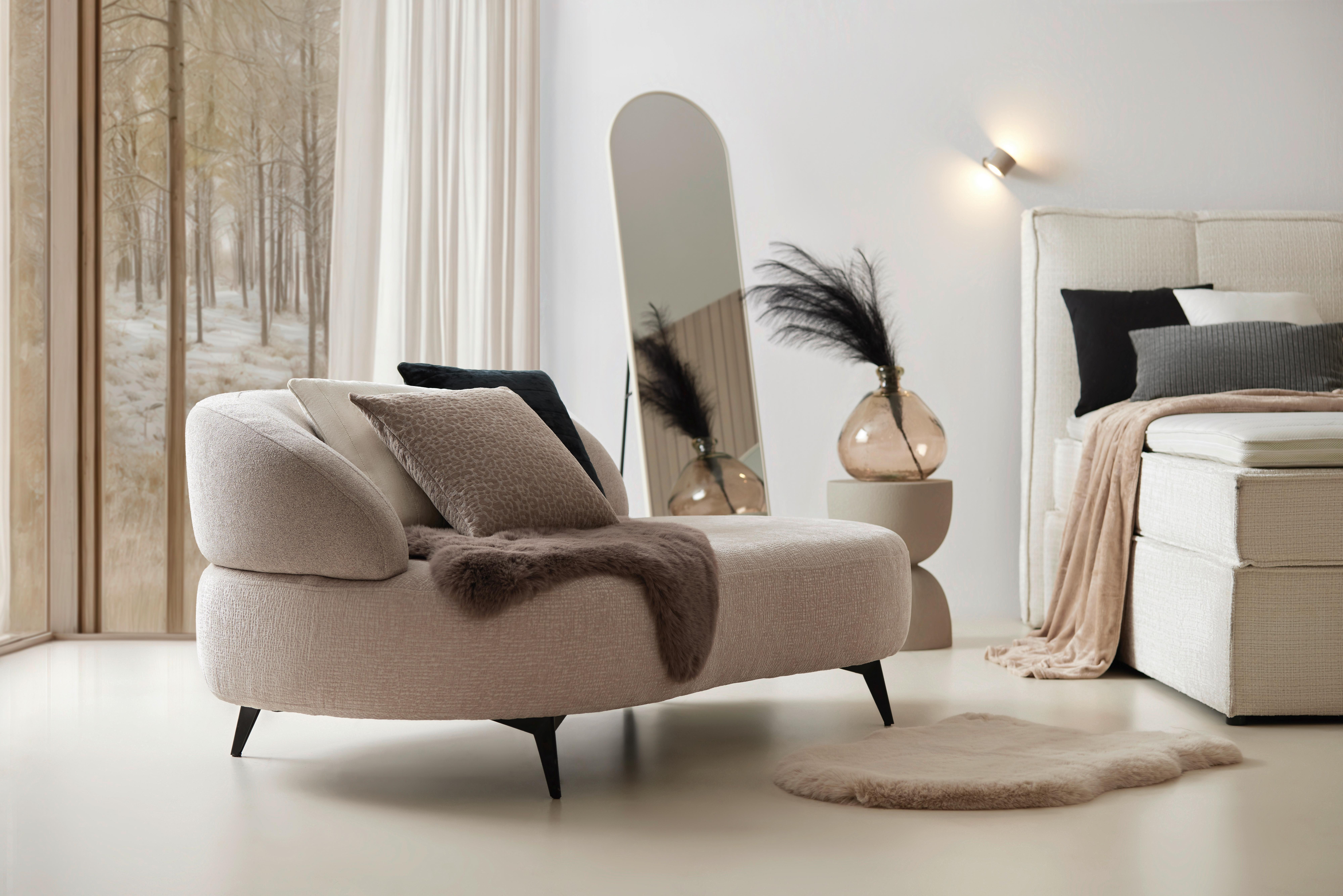 Svetlá spálňa s oblou recamierou v béžovom čalúnení, doplnená zrkadlom, mäkkými textíliami a jemným osvetlením v prírodných tónoch.