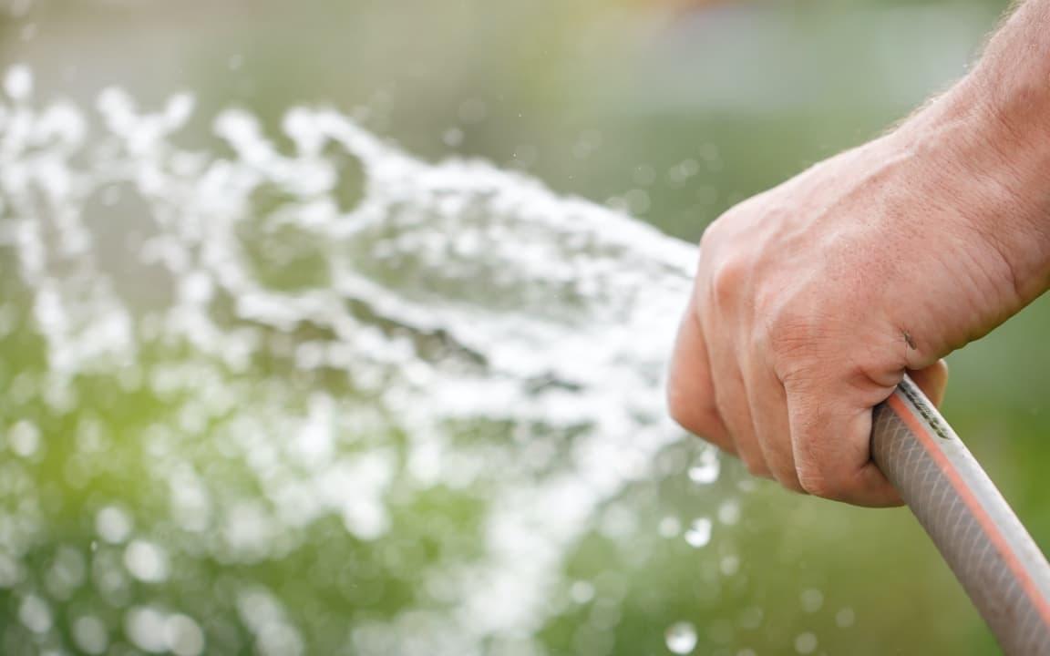 Gartenschlauch in Hand versprüht Wasser
