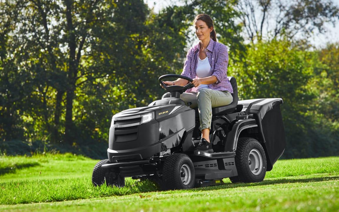 Frau mäht Rasen mit Mähtraktor