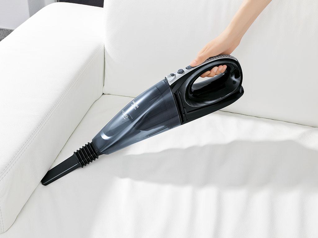 Handstaubsauger wird auf einer Sofa angewendet