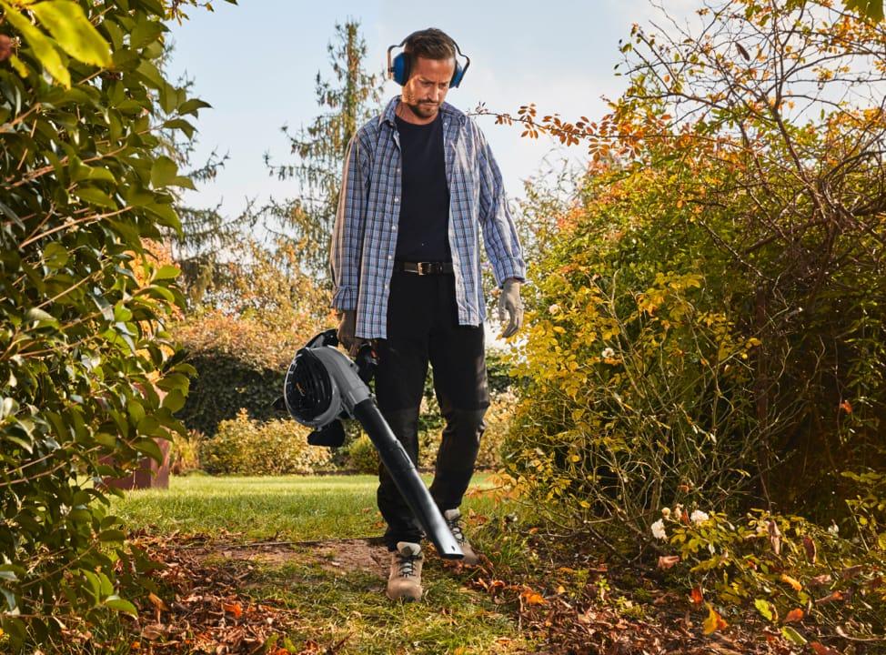 Mann bläst Laub mit einem Laubgebläse