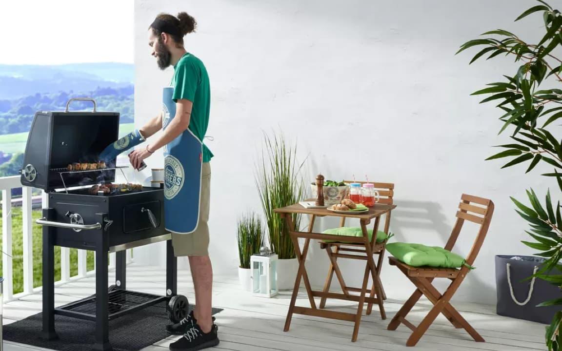 Person vor Griller auf Terrasse
