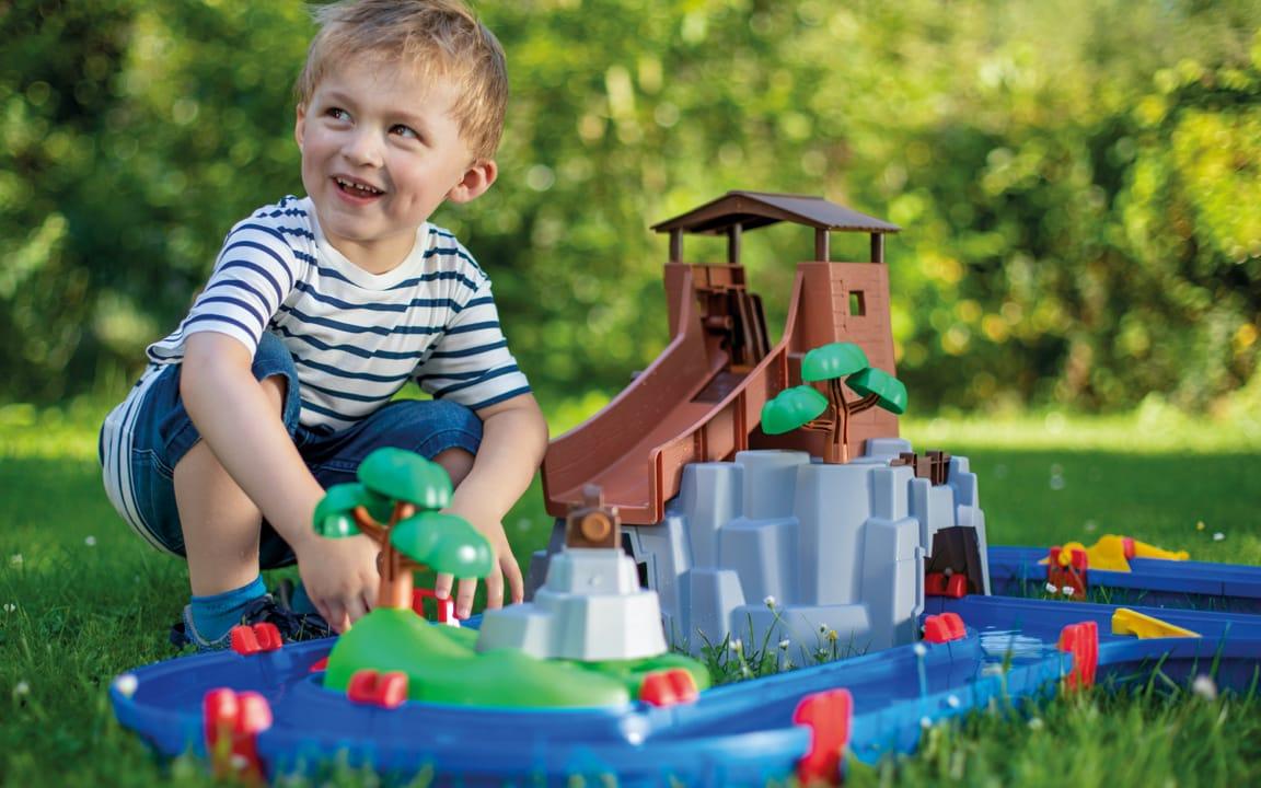 Kind neben Spielzeug im Garten