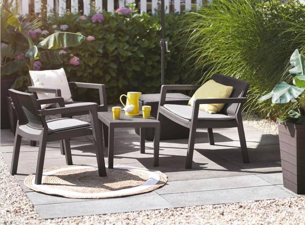 Sitzgruppe aus dunklem Kunstoff im Garten