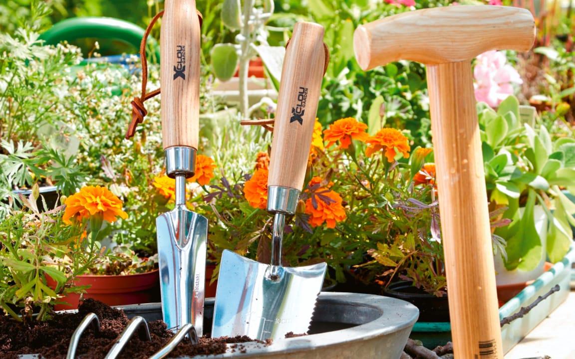 Gartenwerkzeug in Blumentopf vor Blumen