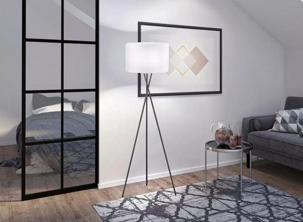 Eine dreibeinige Stehleuchte in einem Wohnzimmer im Loft-Stil.