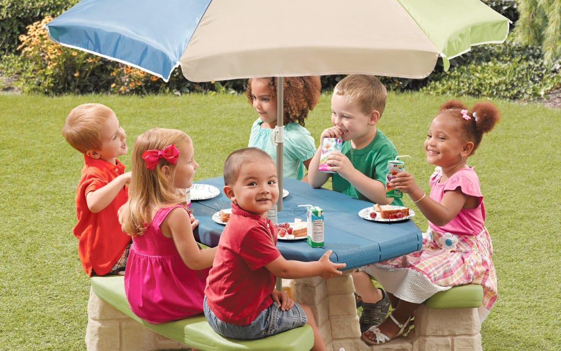 Gruppe von Kindern essen von kleinem Tisch
