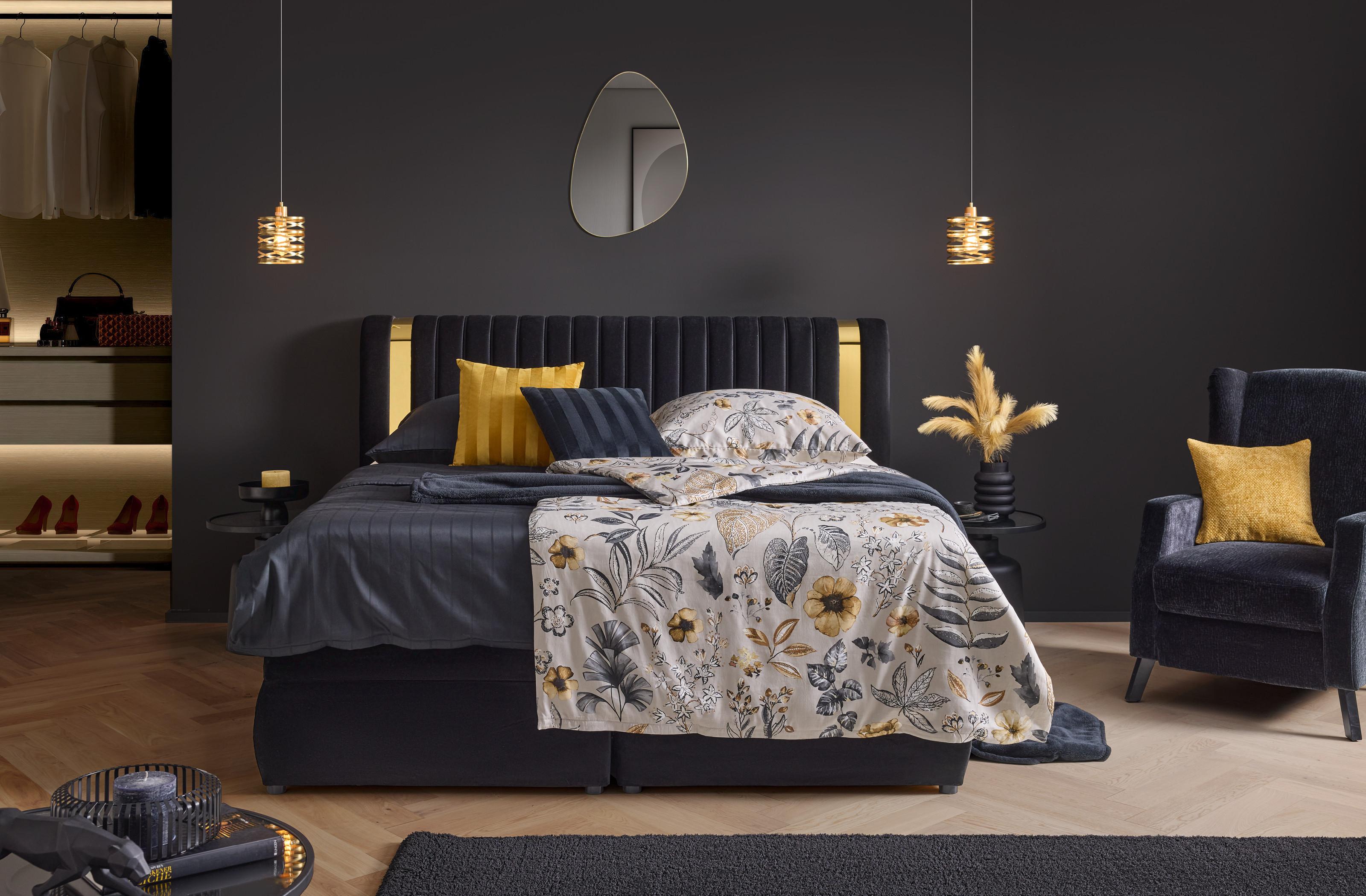 Elegantná spálňa Golden Dreams: čierne lôžko so zlatými detailmi, kvetinové obliečky a štýlové dekorácie pre luxusný vzhľad.