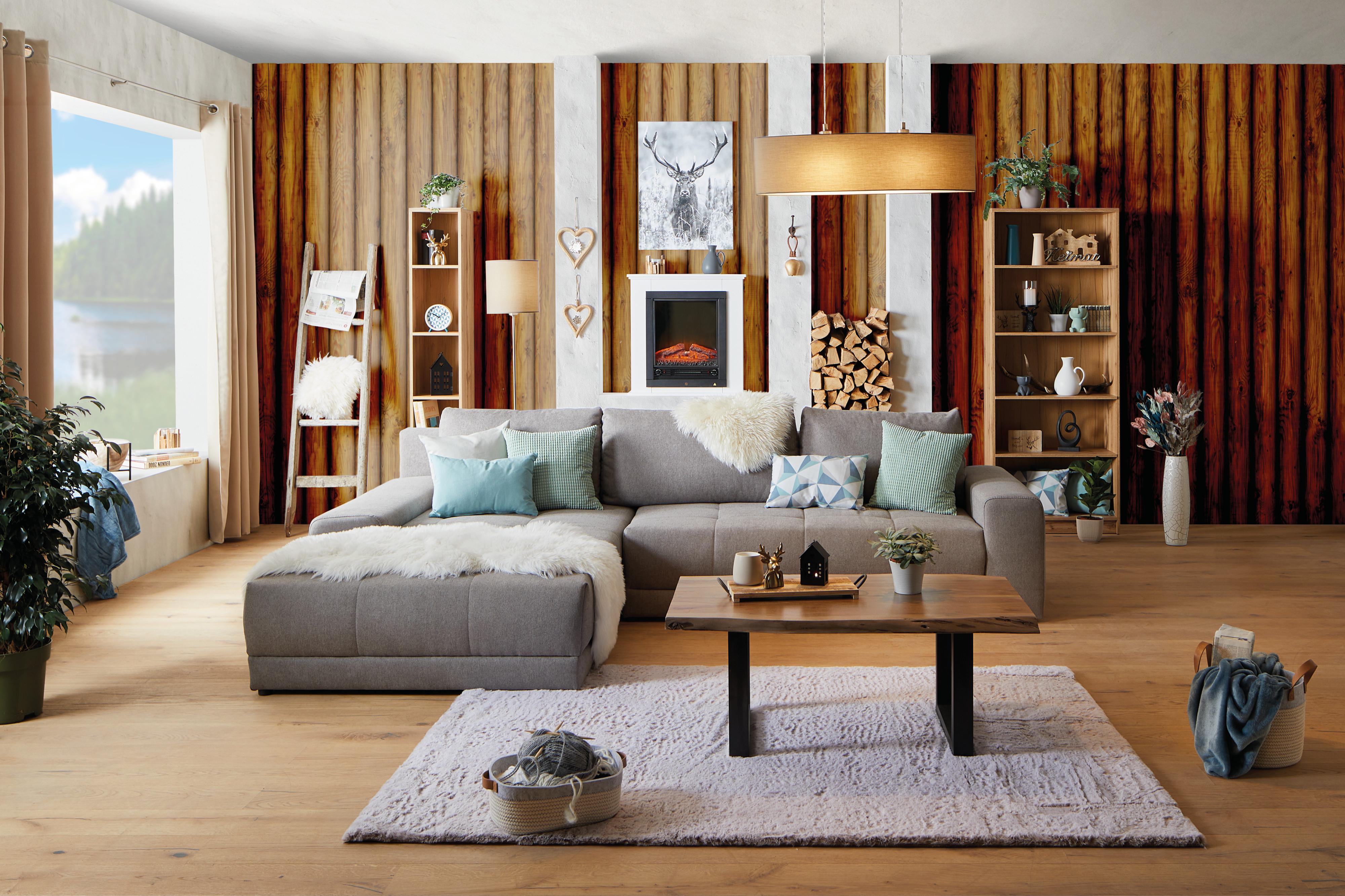 Kuschelige Kissen & Decken auf einem grauen Sofa.