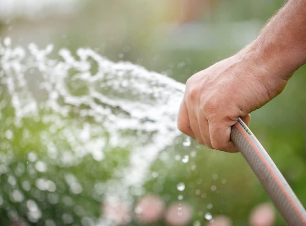Gartenschlauch in Hand versprüht Wasser