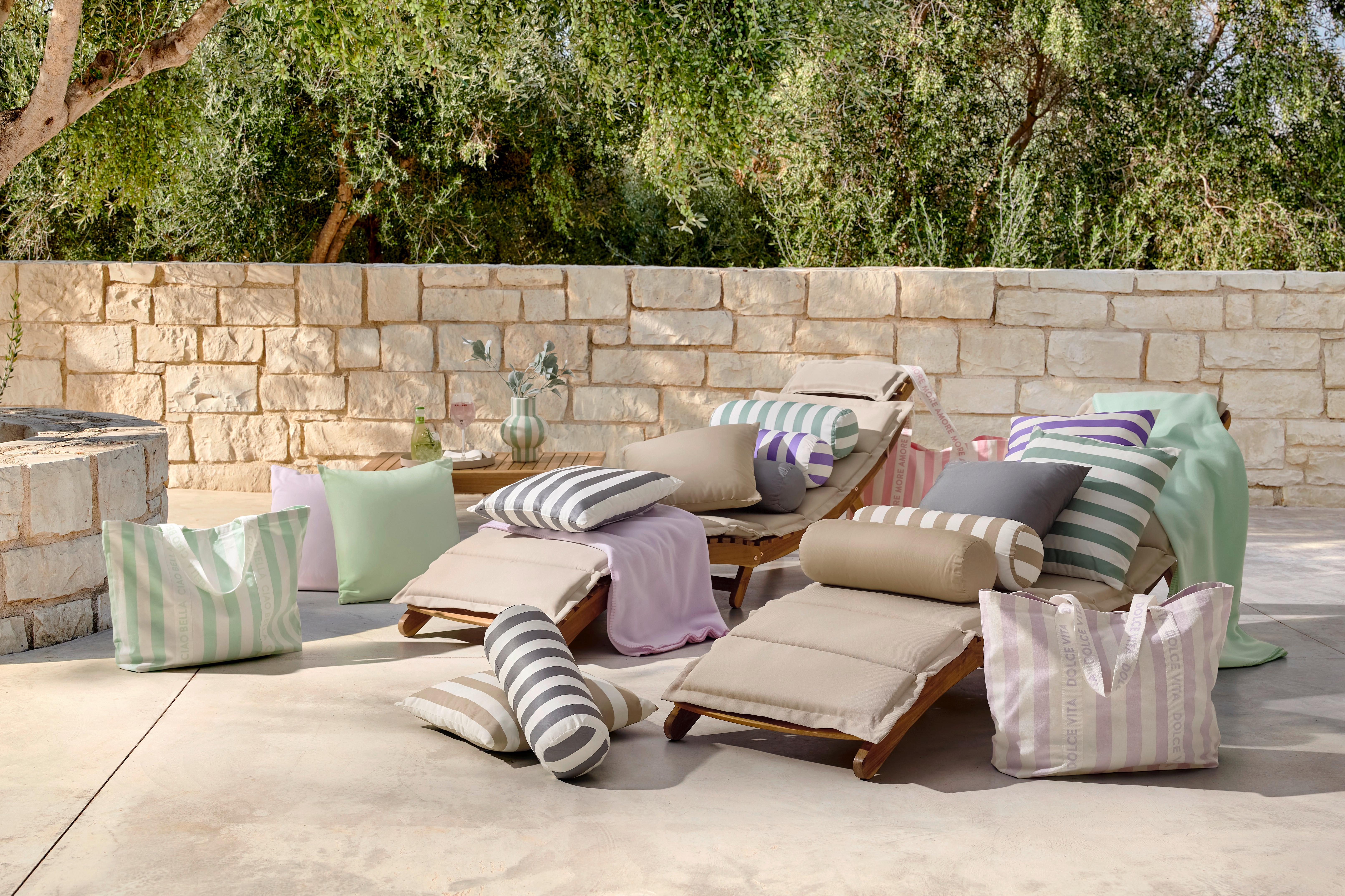 Dve záhradné ležadlá na terase s outdoor vankúšmi a dekami v pastelových farbách pre pohodlný letný relax pri bazéne.