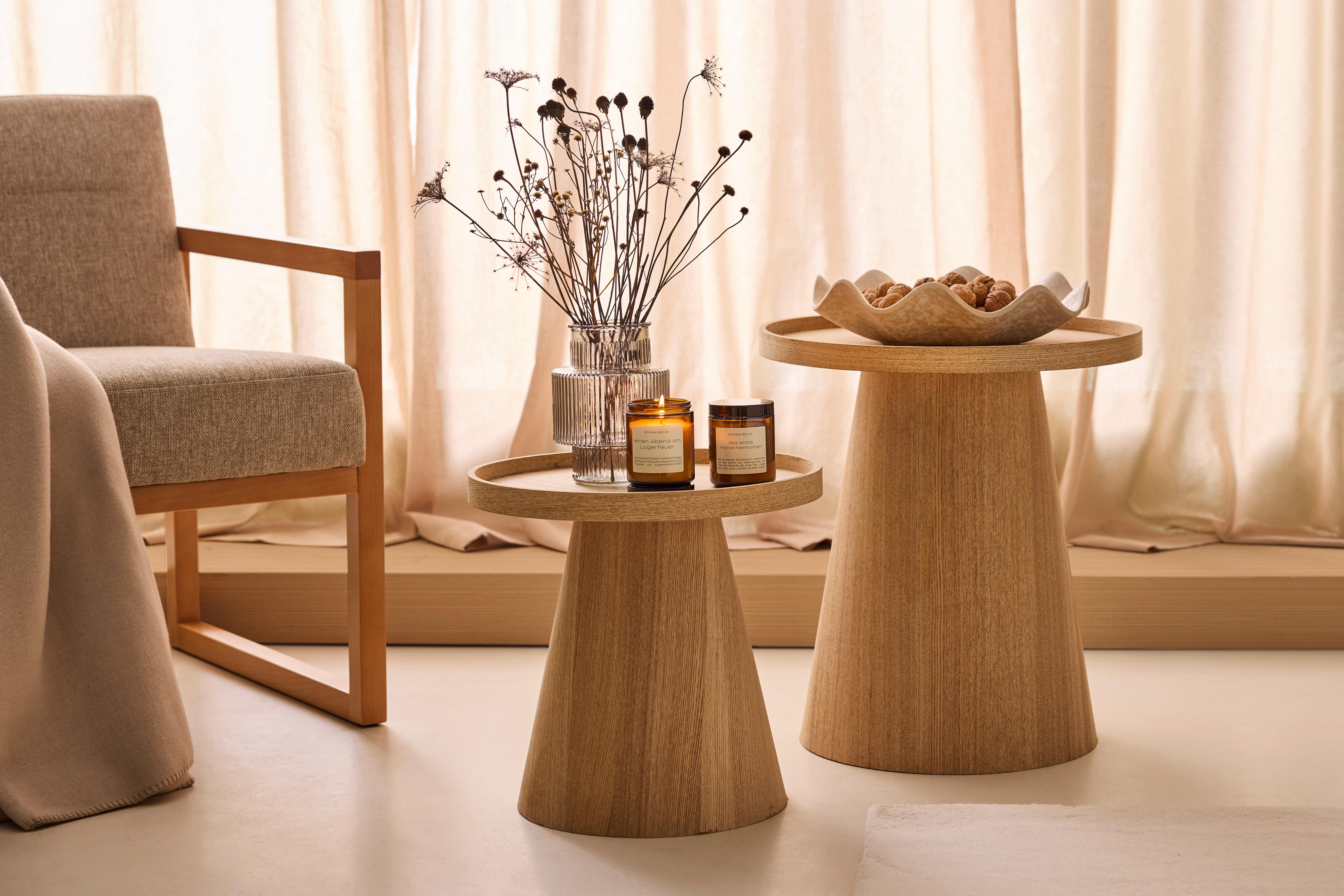 Drevené príručné stolíky s vázou, sviečkami a misou v interiéri ladenom v štýle Japandi.