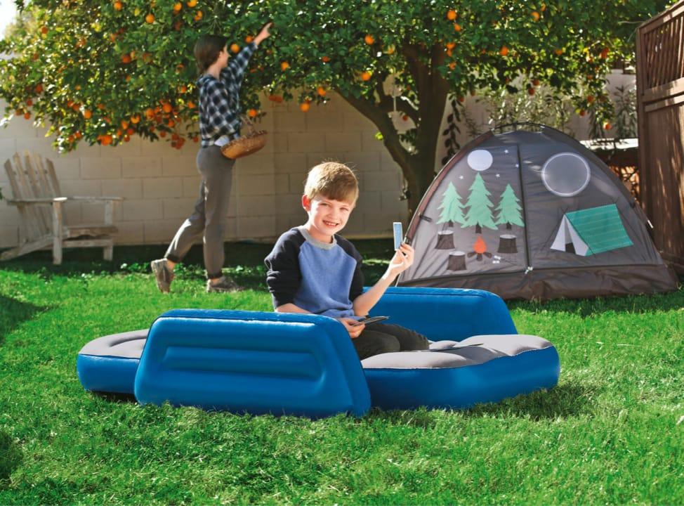 Kind auf blauer Luftmatratze im Garten