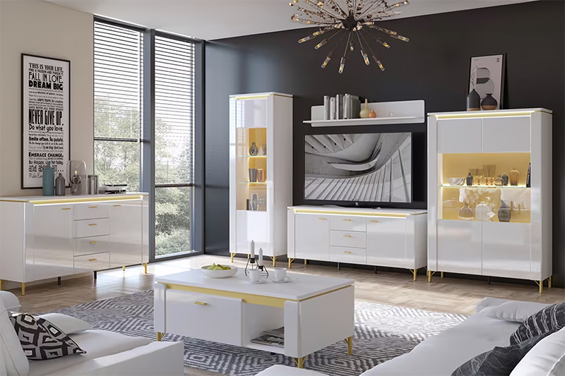 Modern nappali fényes fehér szekrénysorral arany részletekkel, vitrines LED megvilágítással és elegáns, sötét falú enteriőrrel.