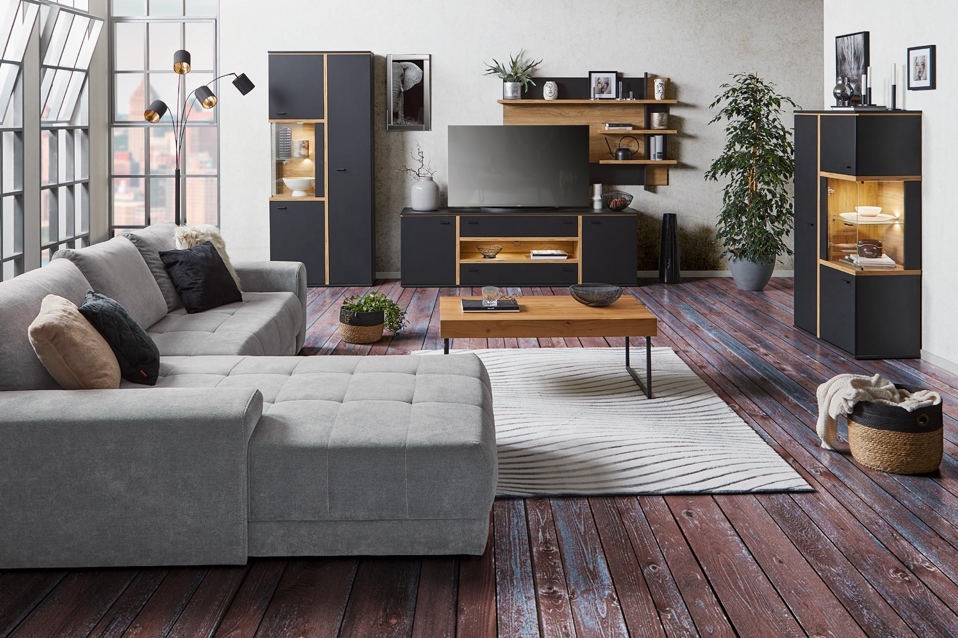 Wohnzimmer mit grauem Sofa und schwarzer Wohnwand