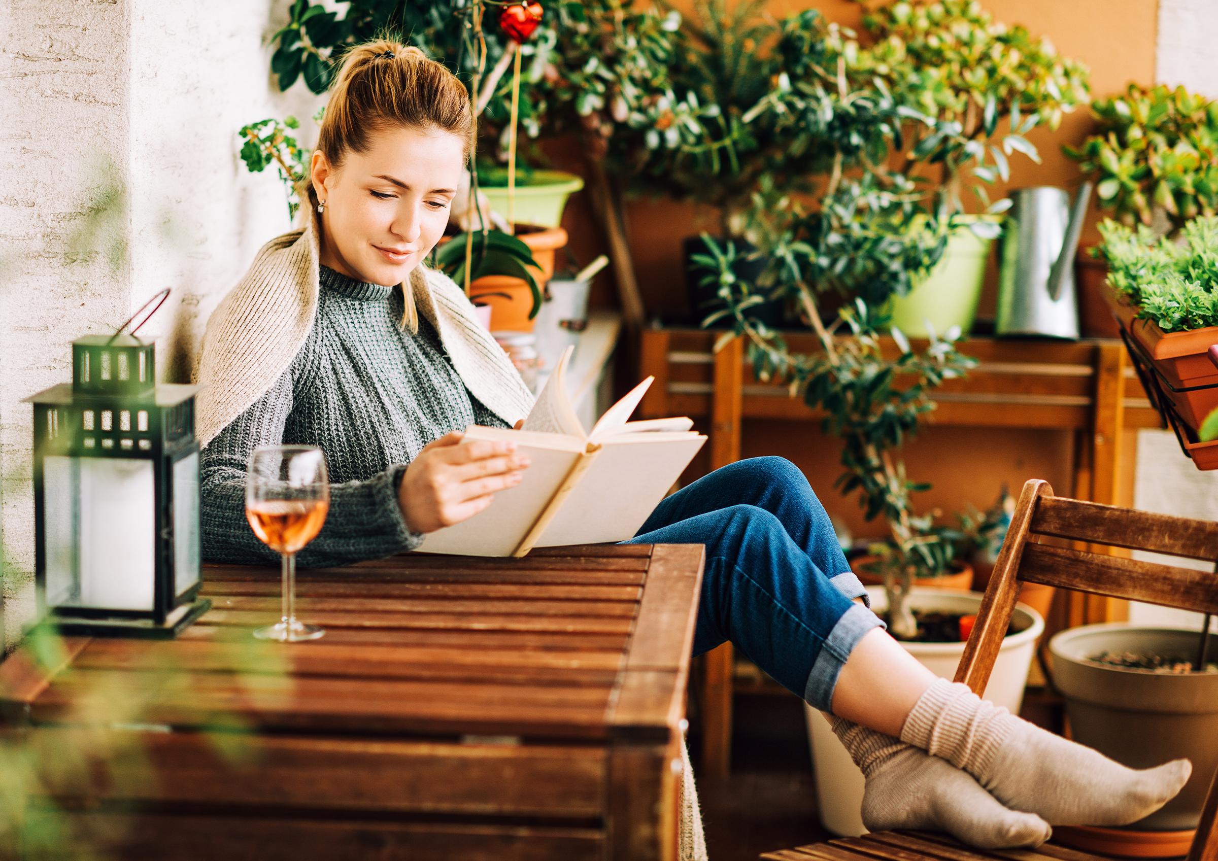 Frau sitzt im Garten und ließt ein Buch
