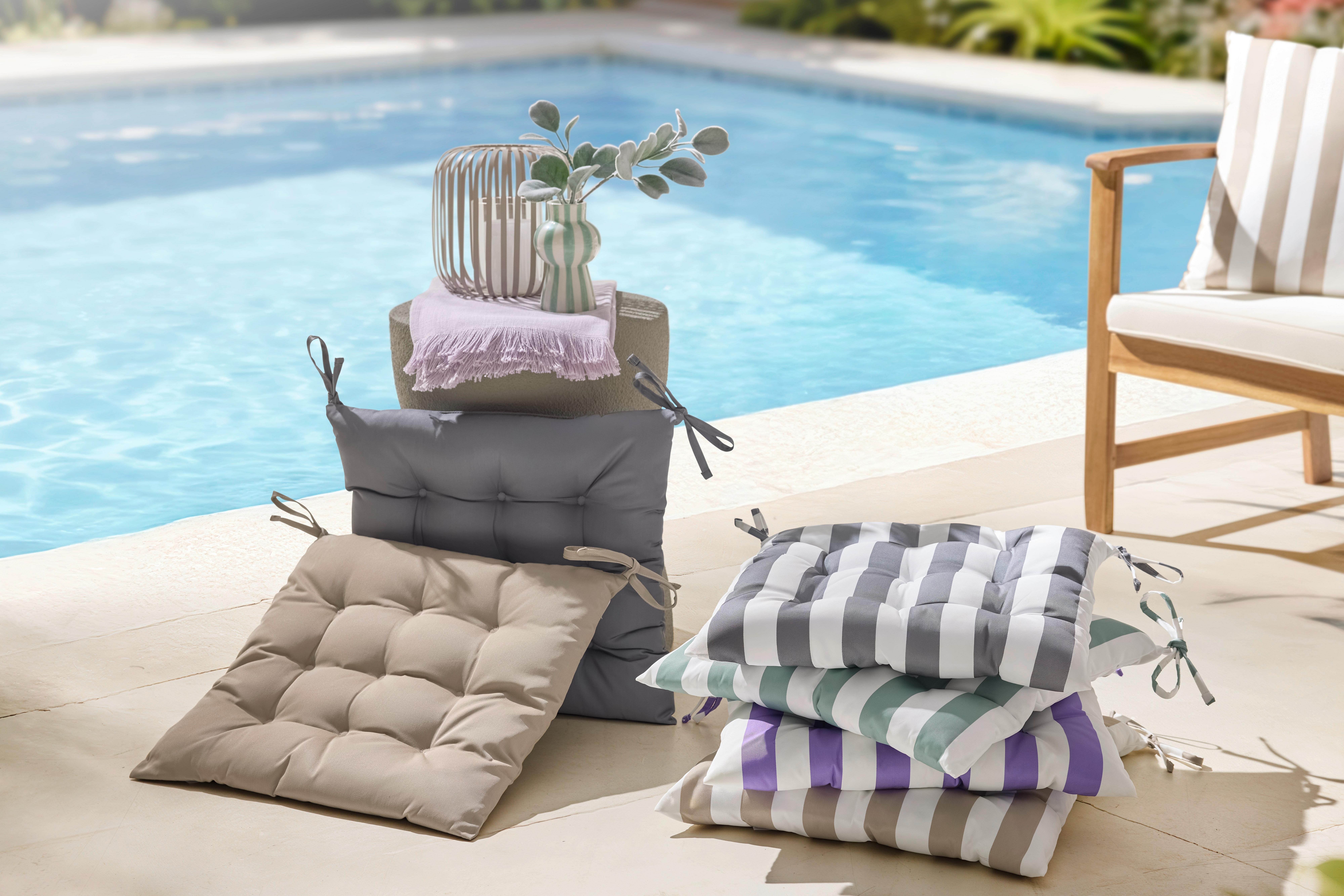 Outdoor sedáky a podsedáky na záhradné sedenie v pruhovaných vzoroch pri bazéne so stolíkom a dekoráciami na letnú terasu.